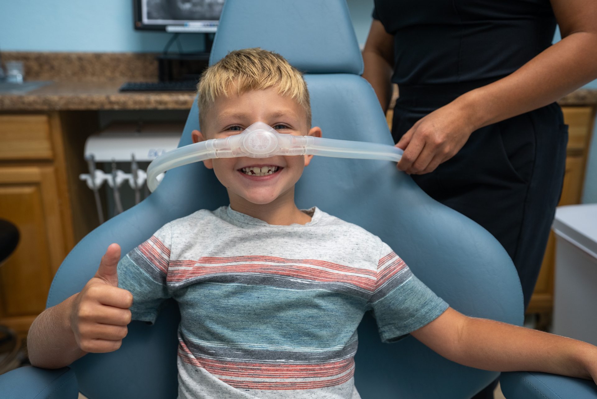 Smiling boy giving a thumbs up while relaxing with nitrous oxide at Cool Kid Dental