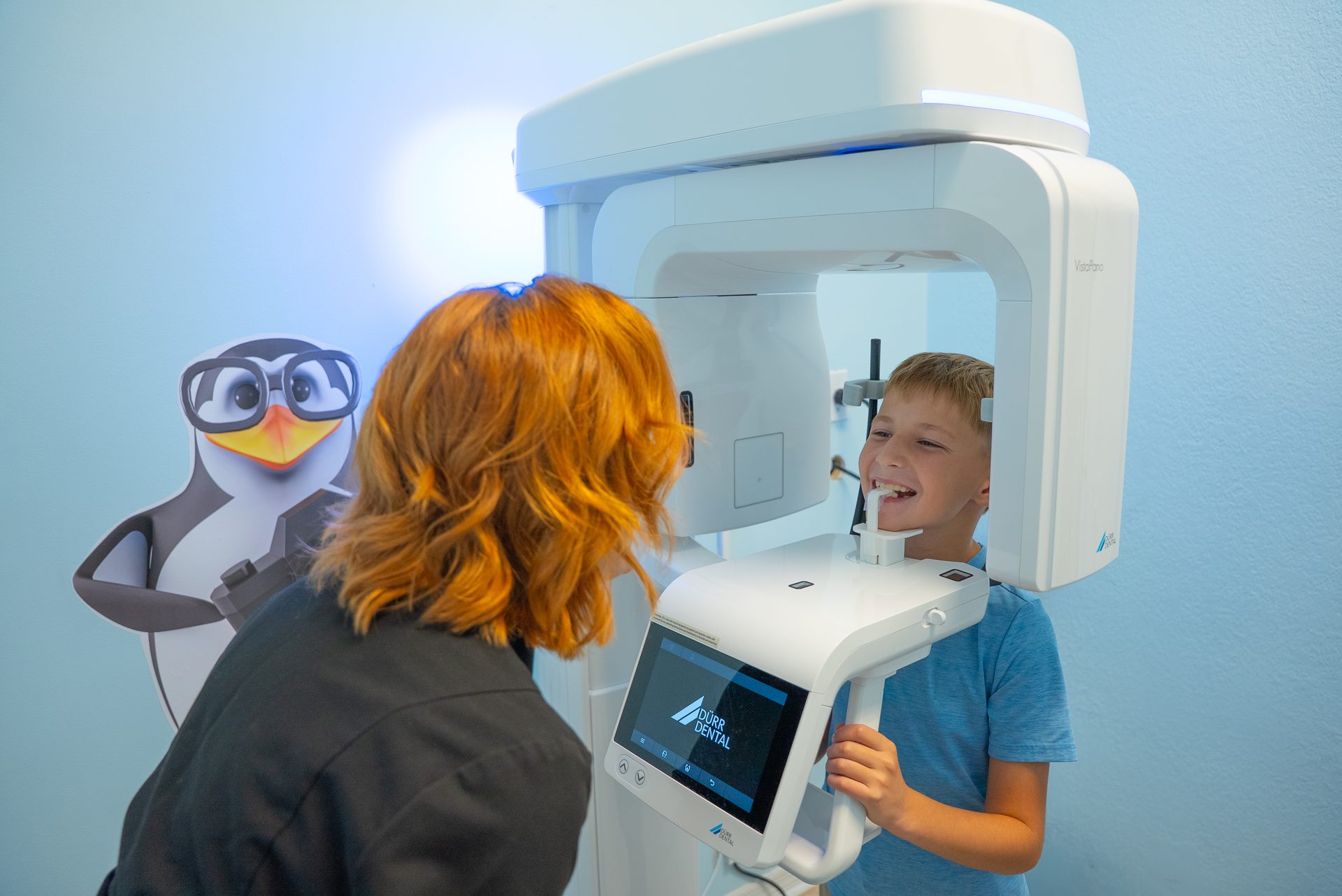 Cool Kid Dental assistant helping a smiling boy with a low-radiation digital X-ray
