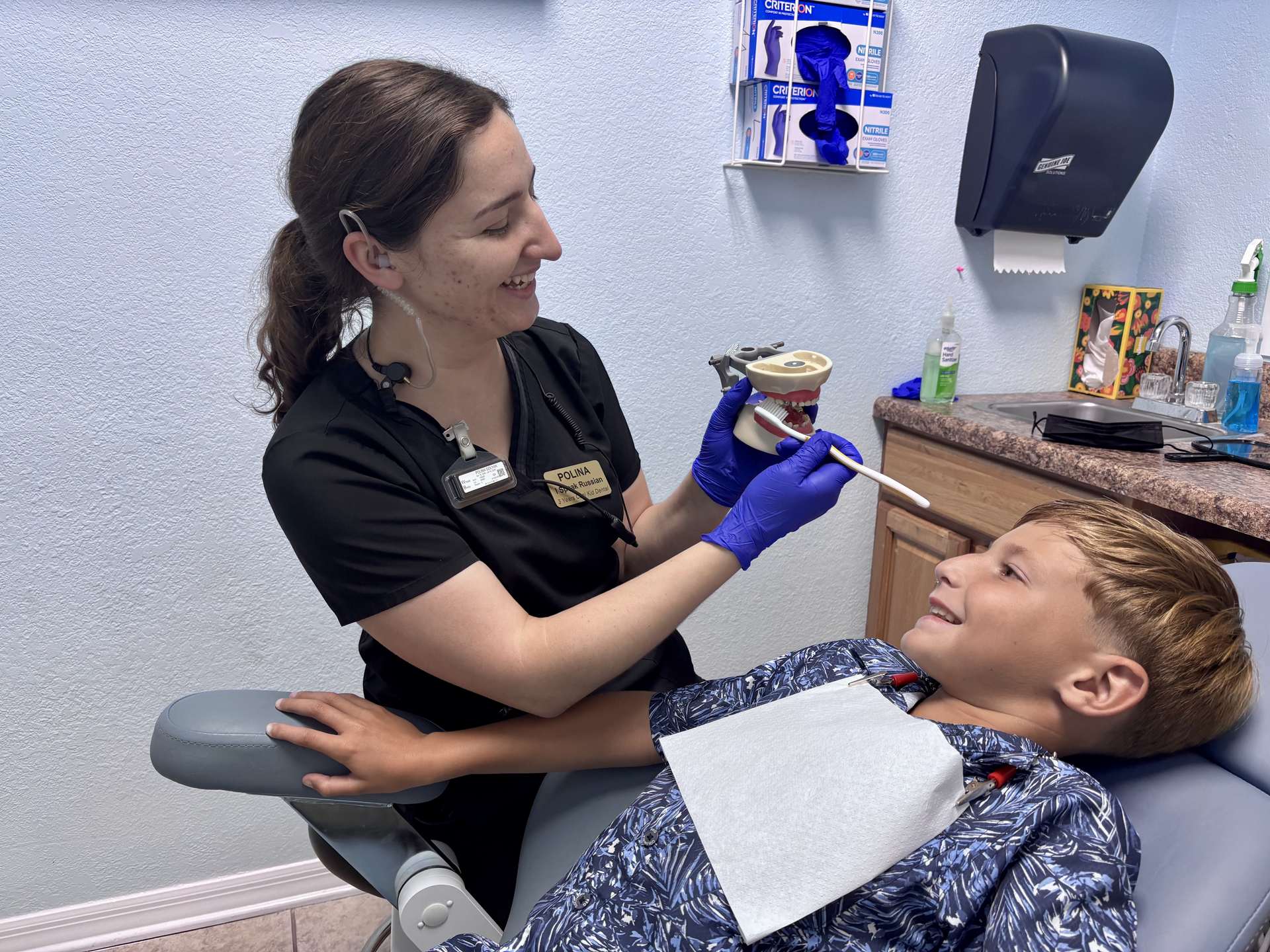 Cool Kid Dental assistant showing a smiling boy the dental tools before his cleaning