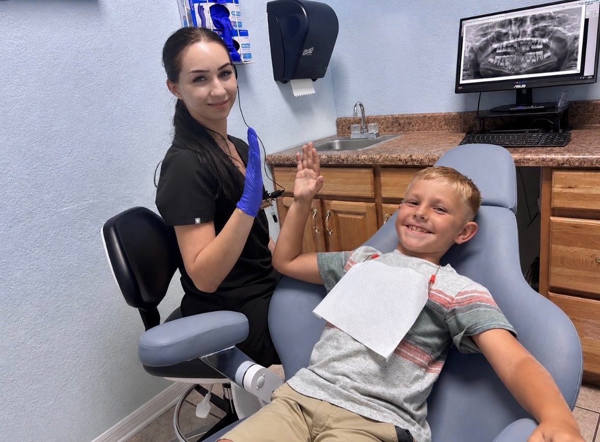 Cool Kid Dental assistant giving a happy boy a high five in the dental chair