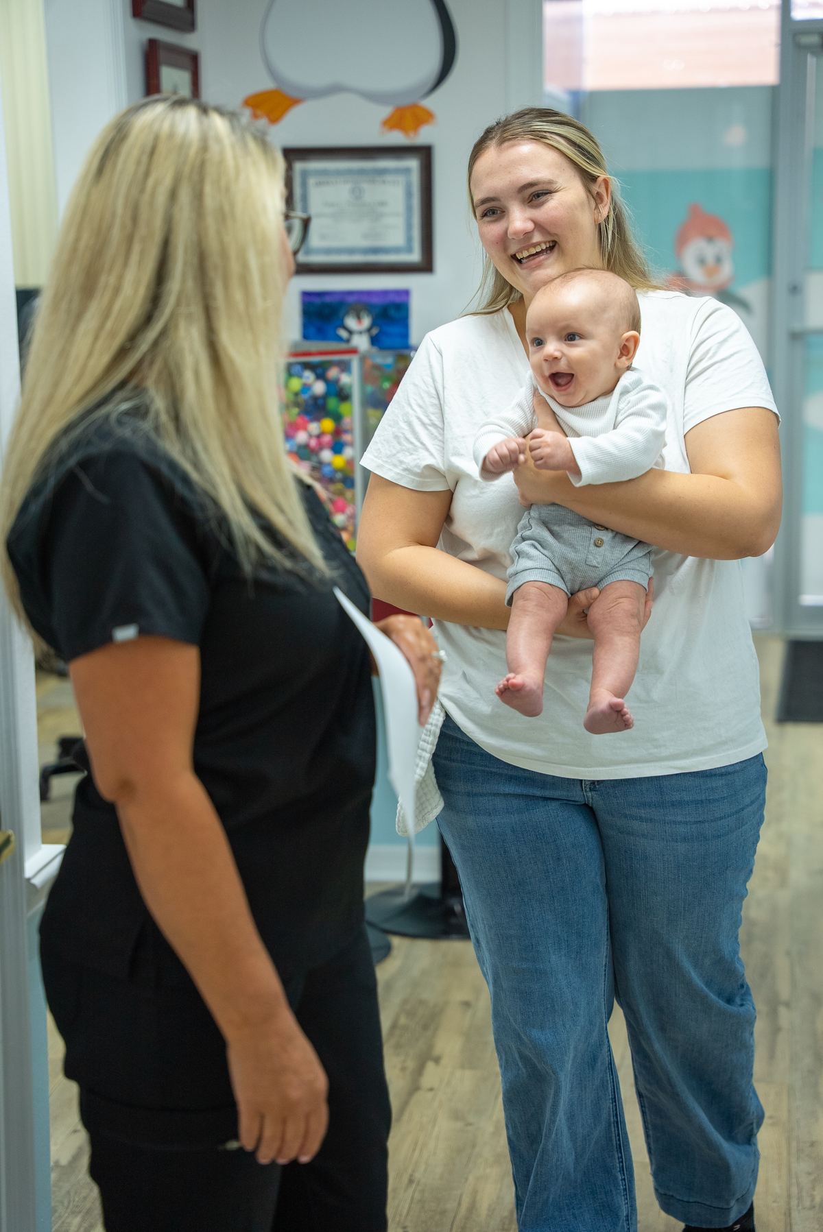 Cool Kid Dental team member welcoming a smiling mom and her baby at the North Port office